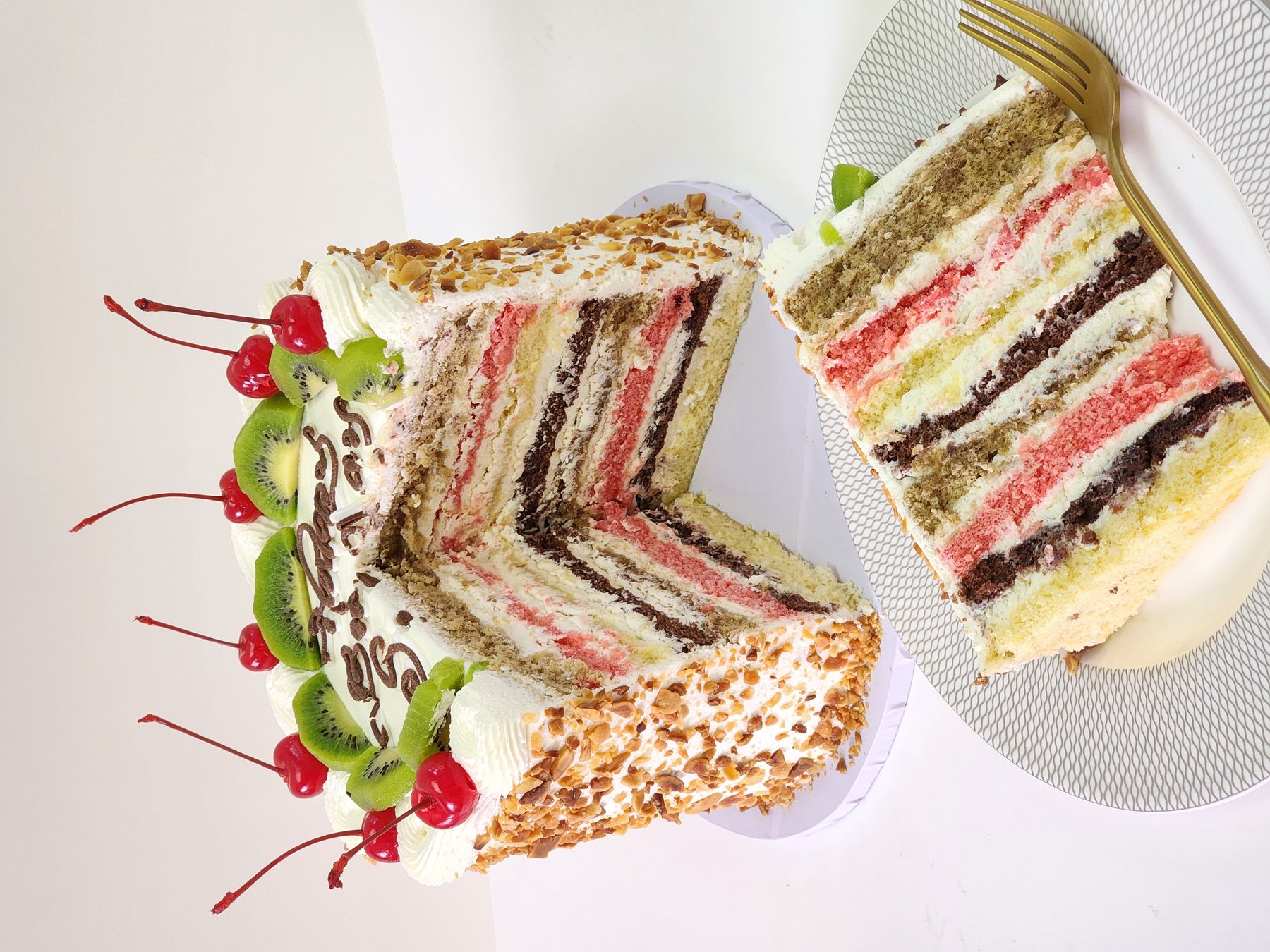 Sliced layered celebration cake with cherries and kiwi